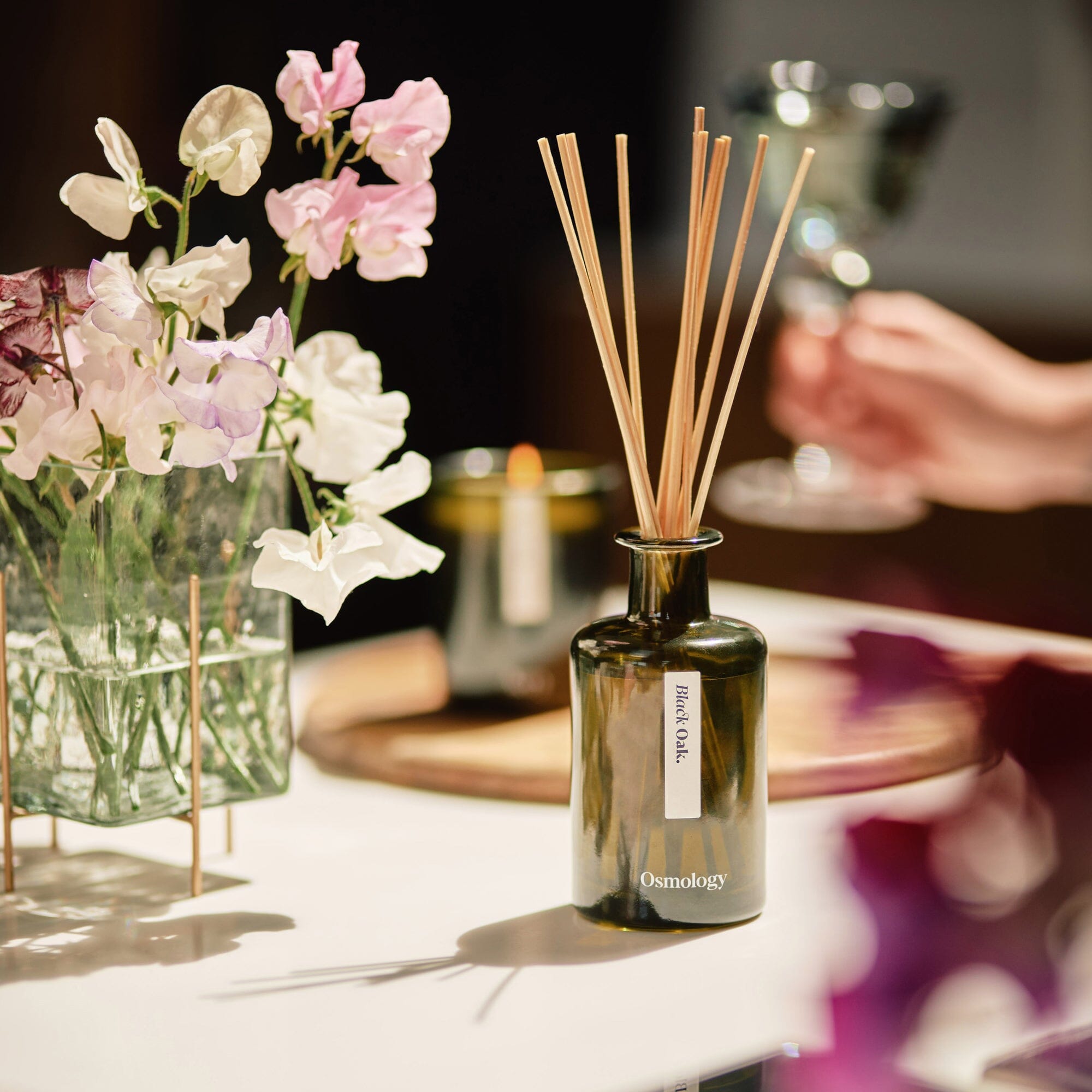 black oak reed diffuser bottle in sunny kitchen setting next to sweet peas