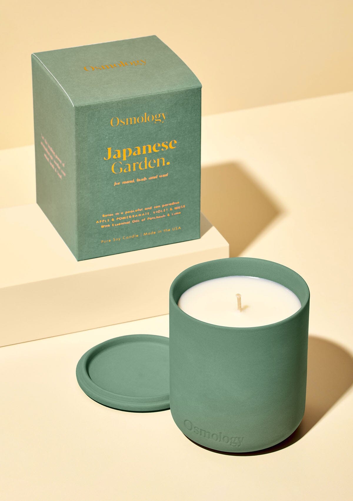 Green Japanese Garden candle by Osmology displayed next to product packaging on cream background 