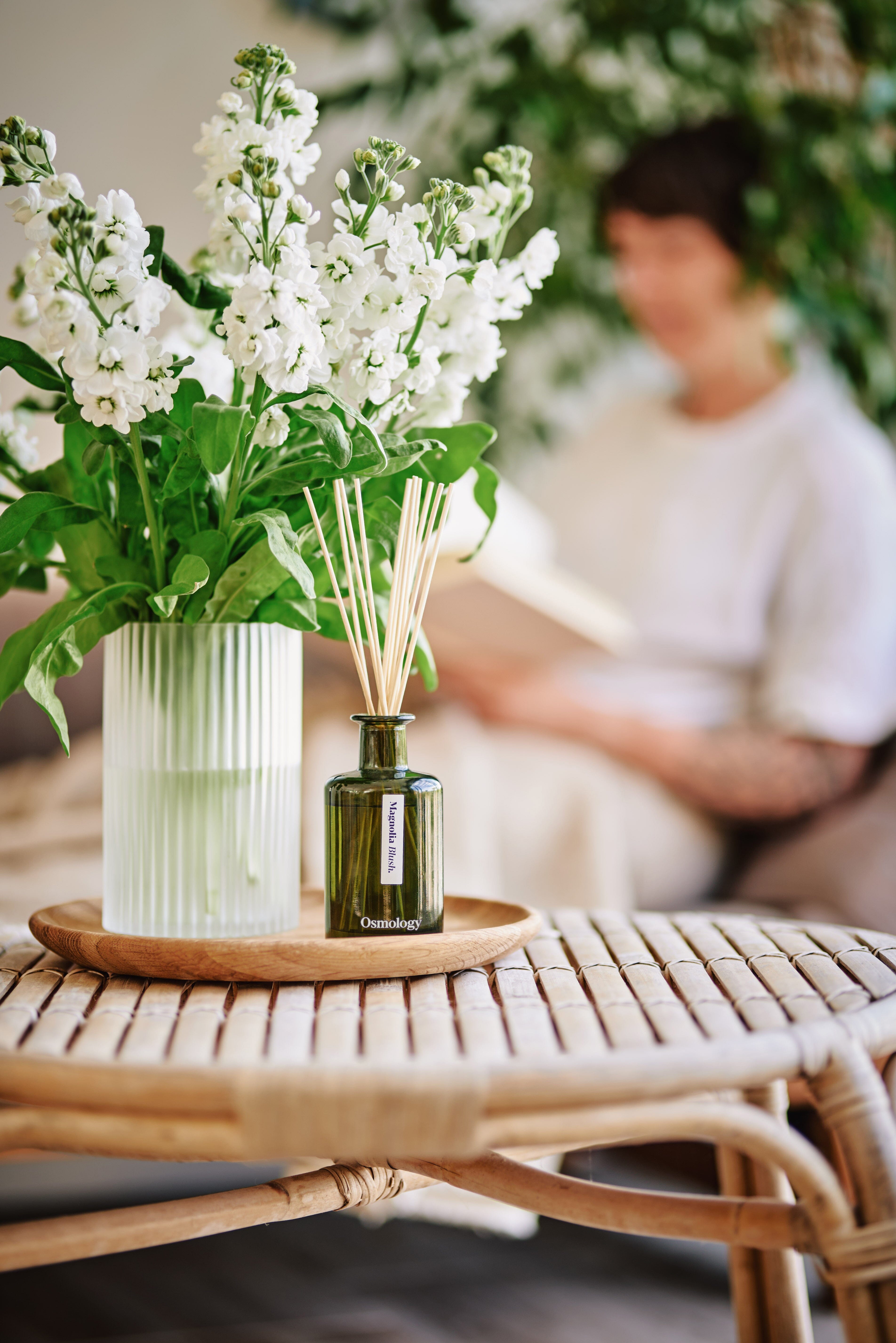 Magnolia Blush Diffuser by Aery sat next to vase of white flowers 