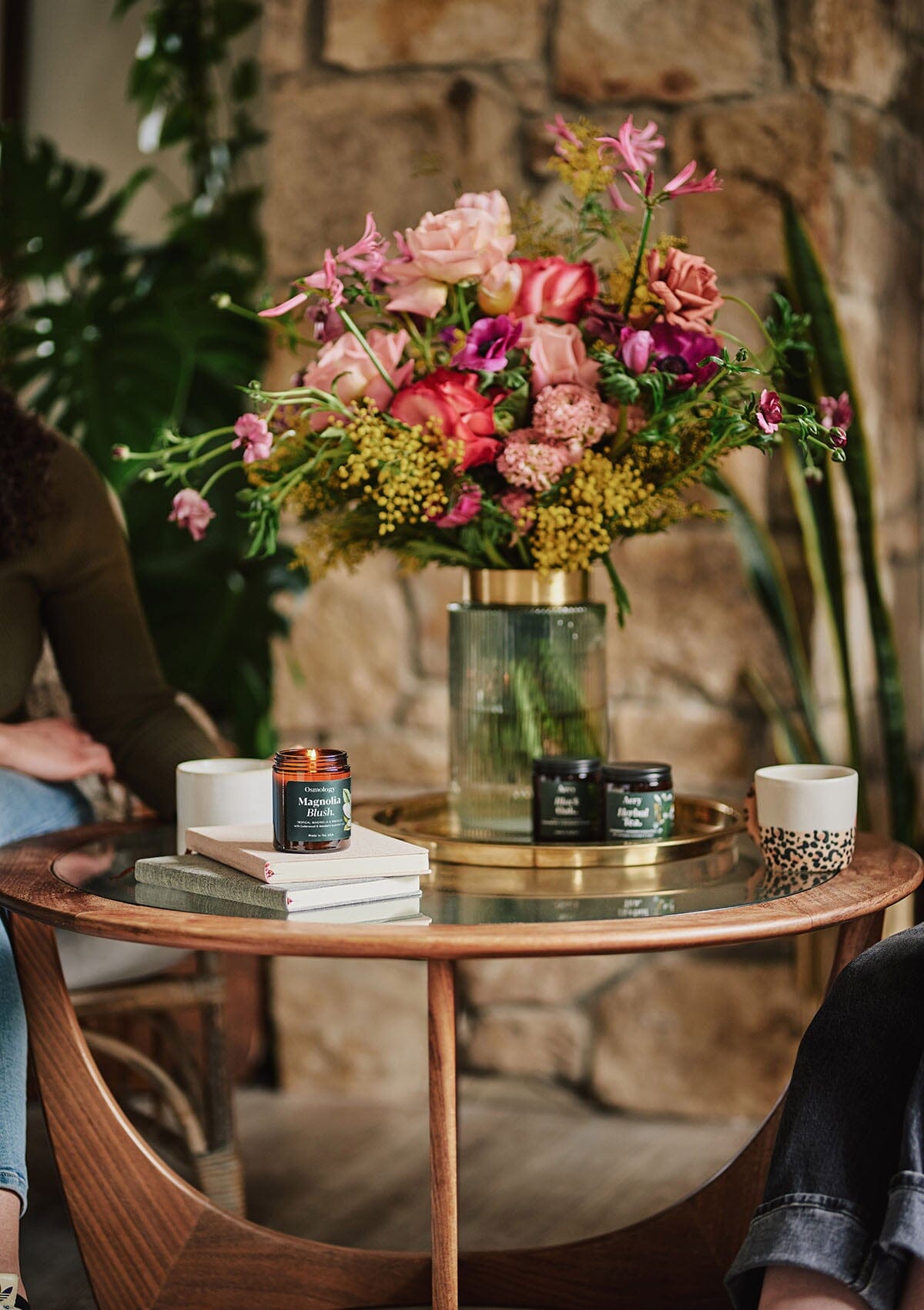 Magnolia Blush jar candle by osmology sat on circle table with bunch of pink flowers 