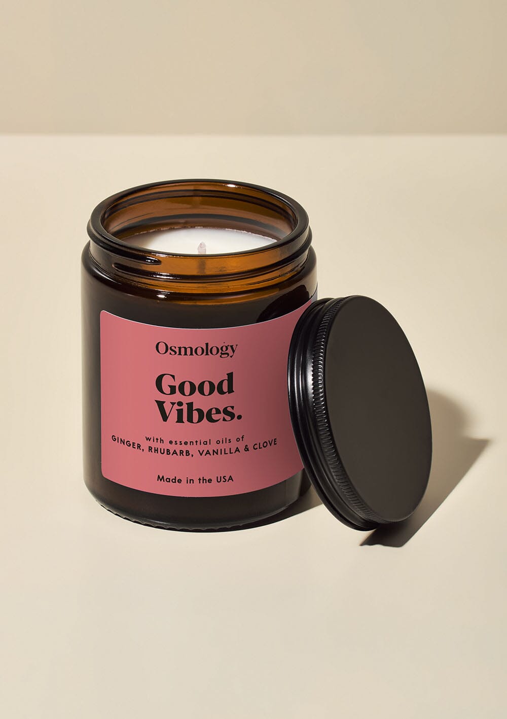 Osmology Good Vibes jar candle with lid open, on cream background