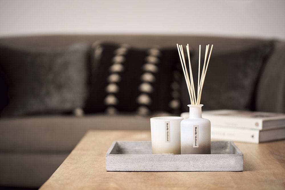 Osmology Heavily Meditated diffuser and candle on grey tray, on table