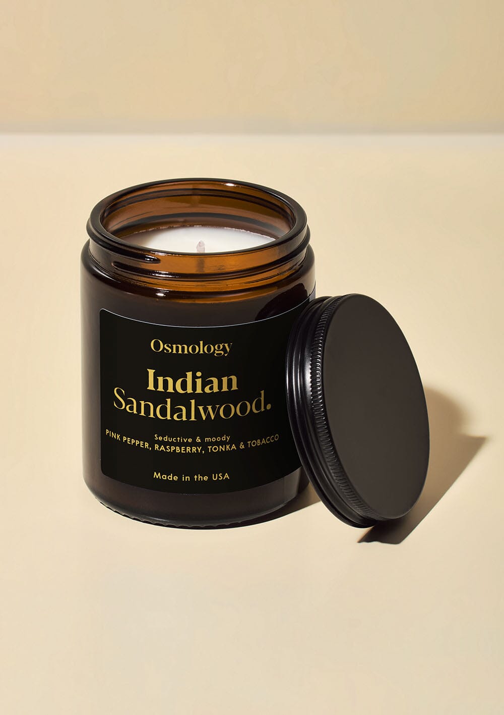 Osmology Indian Sandalwood jar candle with open lid on yellow cream background