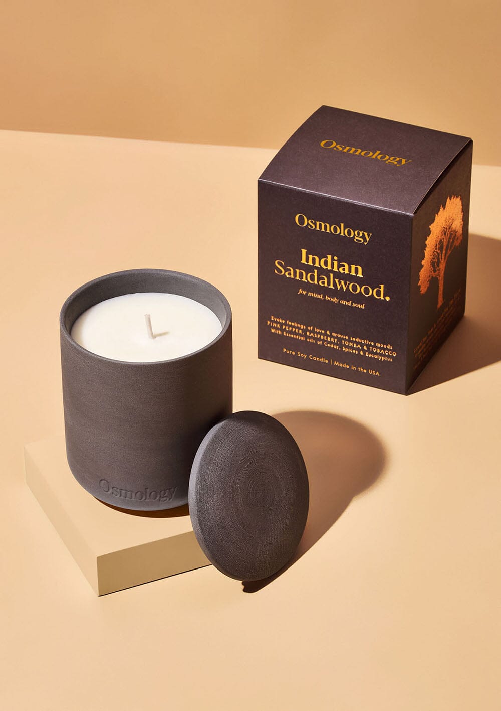 Osmology black ceramic indian sandalwood scented candle displayed next to decorative product packaging