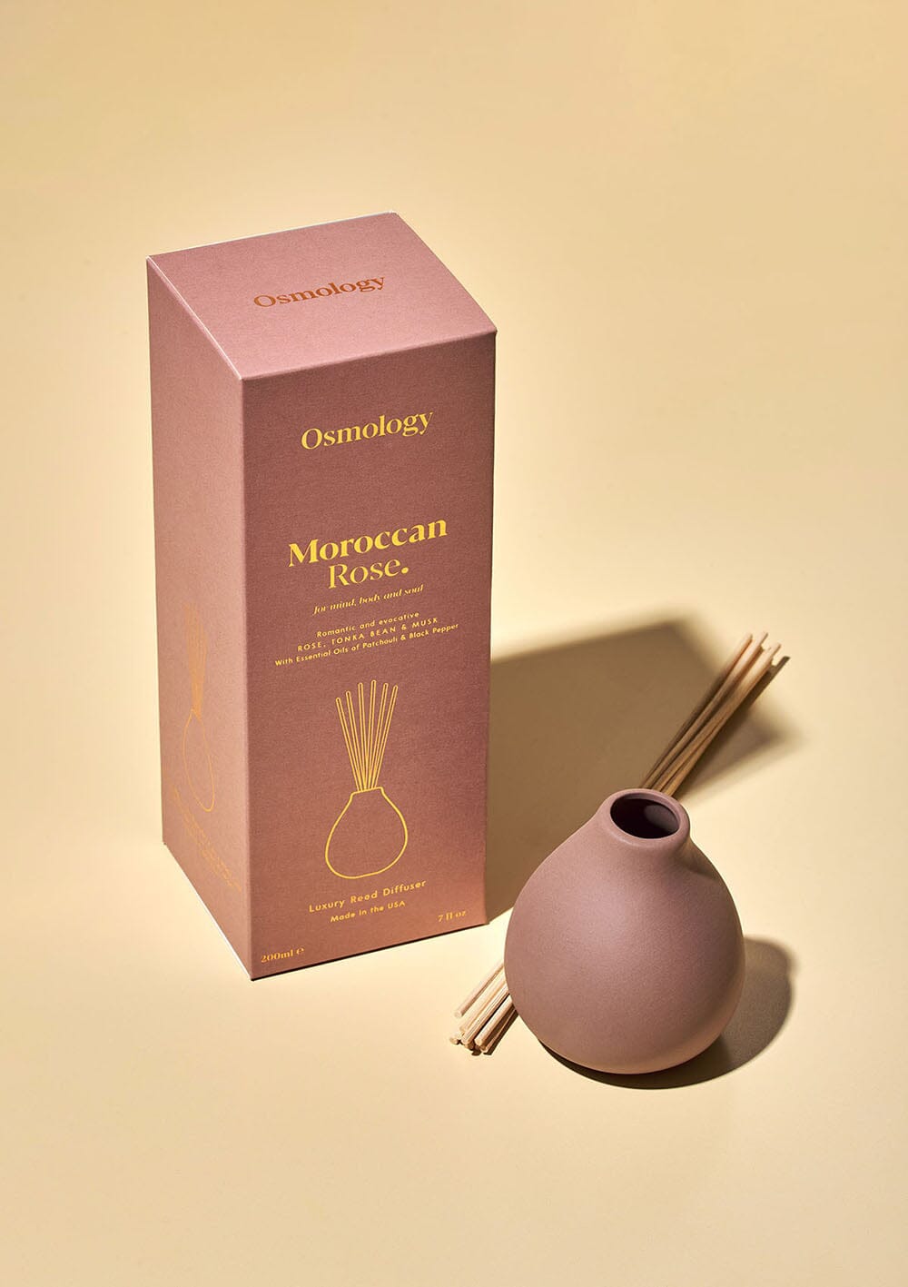 Osmology Moroccan Rose reed diffuser with reeds with product packaging on cream background