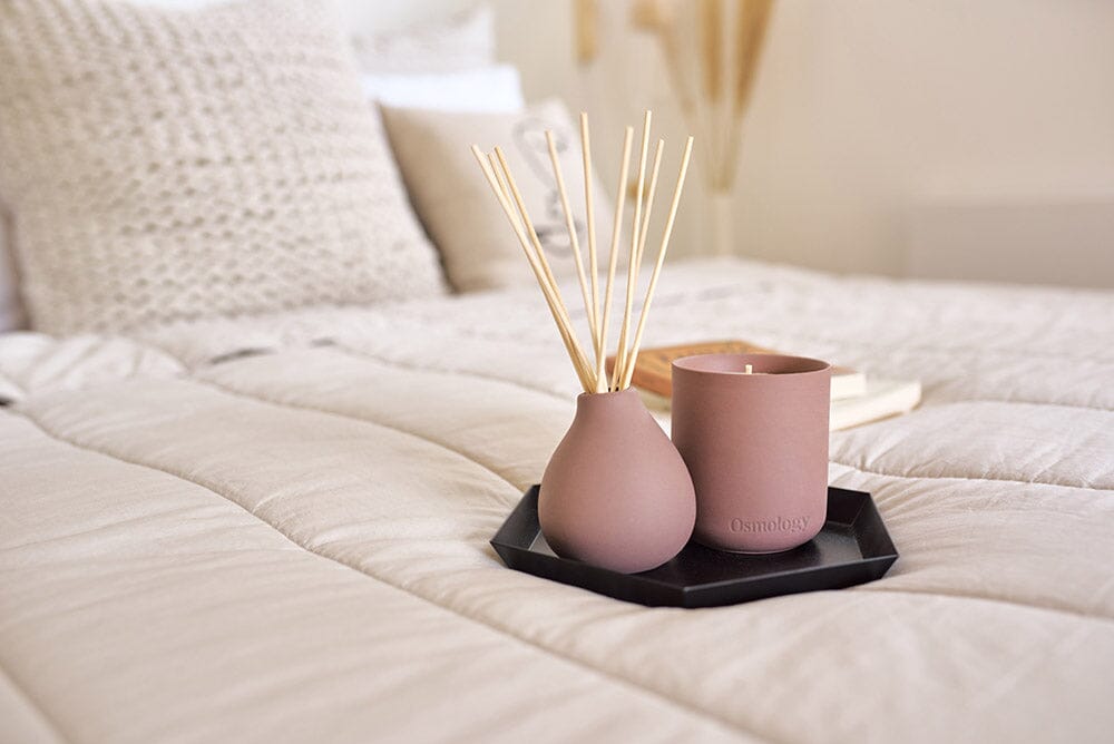 Osmology Moroccan Rose diffuser with Moroccan Rose candle on black tray on bed