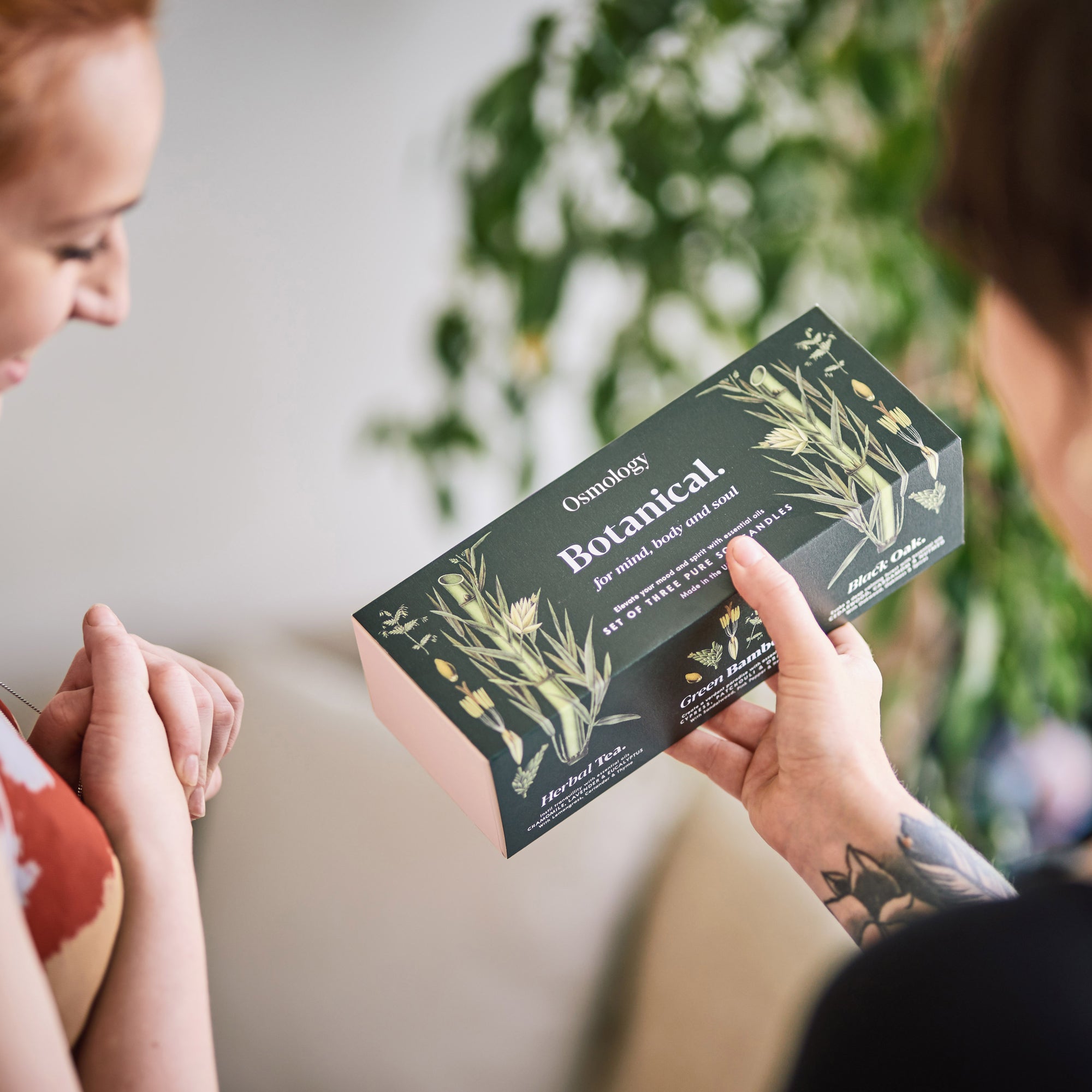 person handing another person osmology botanical gift set