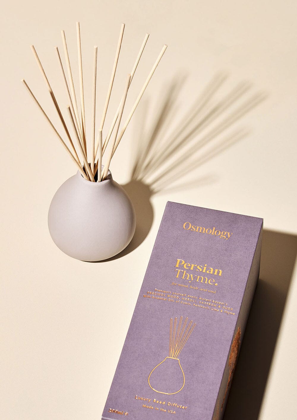 Osmology Persian Thyme grey ceramic reed diffuser next to product packaging on a cream background