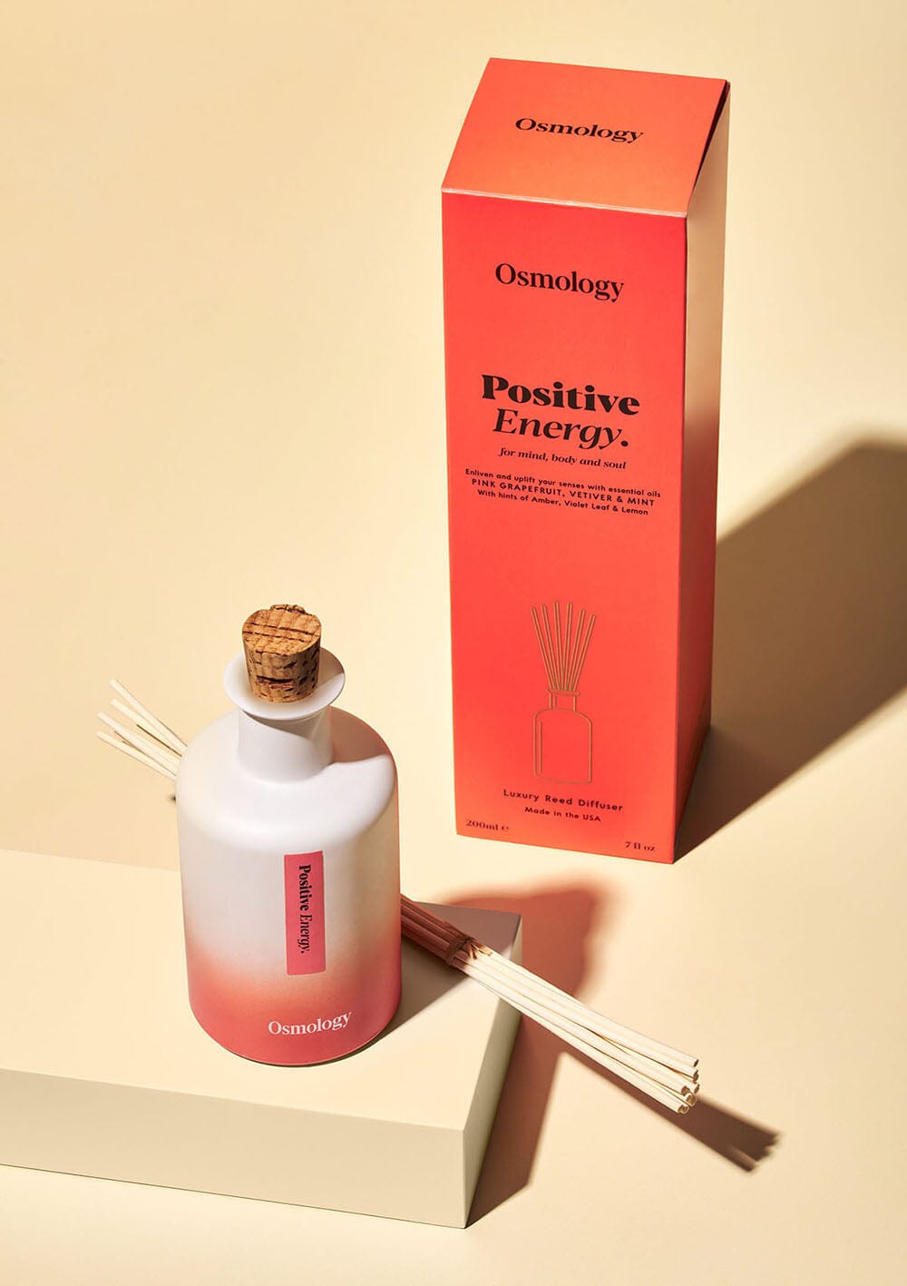 Positive energy reed diffuser and product packaging on a cream background